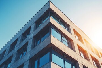 A modernist building with a clean, angular facade is starkly set against a clear blue sky, showcasing the building's sharp lines and contemporary architectural style.