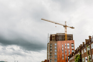 Fototapeta premium Construction crane and modern building under cloudy sky