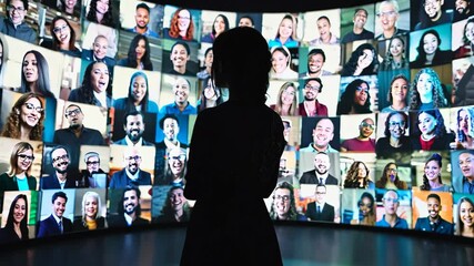 Woman Silhouette Looking at Diverse, Smiling Faces on Large Screen Display: Social Media, Global Connection, and Virtual Communication Concept