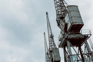 Industrial cranes against cloudy sky, an upward perspective of three large industrial cranes reaching skyward against a cloudy backdrop