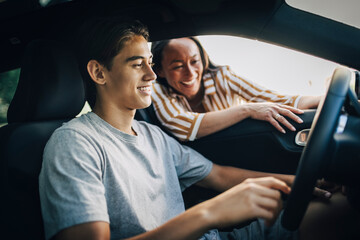Happy mother instructing son driving car