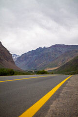 A winding road with yellow lines stretching into the distance, disappearing between towering mountain ranges on either side. A breathtaking blend of rugged nature and serene isolation.