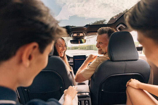Happy father and mother enjoying road trip with sons while sitting in car