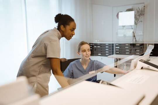 Female healthcare experts discussing over computer while working at hospital