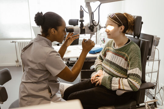 Eye care professional examining patient's eye in clinic