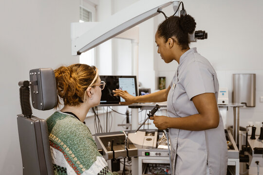 Side view of female Ophthalmologist programming machine during eye test at hospital