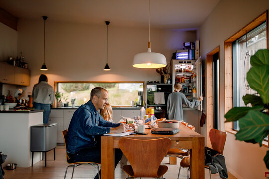 Male freelancer preparing document while sitting at dining table