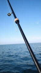 Fototapeta premium A sleek and stylish fishing rod set against a serene blue background, perfect for any angler looking to catch some big fish, fishing hobby, recreational activity, fishing pole