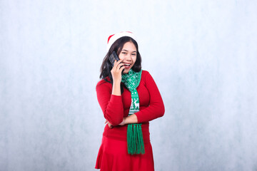 portrait of woman wearing red sweater with Santa hat and scarf celebrating merry christmas, cheerful hug looking at camera phone person via cellphone mobile phone, isolated on white background