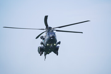 Fototapeta premium The military helicopter is hovering in the air, facing forward at an airshow. Blue background.