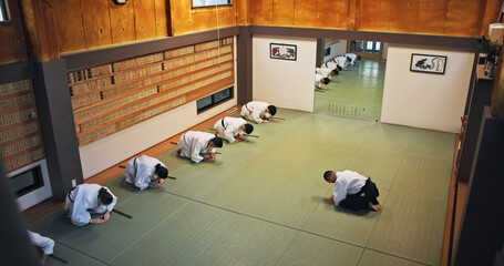 Bow, greeting and people in martial arts studio for practice, training or self defense class. Culture, karate and group of students with respect or etiquette gesture to master in dojo for honor. © M Einero/peopleimages.com