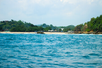 Long sea view with white cliff island with trees in the distance seen from the sea.