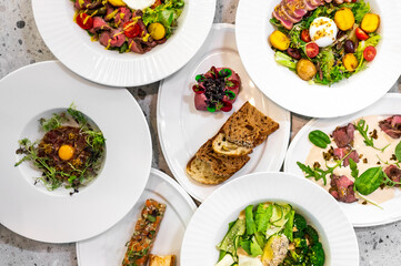 A stylish arrangement of gourmet dishes featuring fresh salads, colorful vegetables, and artisanal bread. Perfect for a restaurant menu or food presentation concept. Vibrant and appetizing.