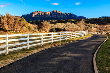 A road with a white fence and a mountain in the background