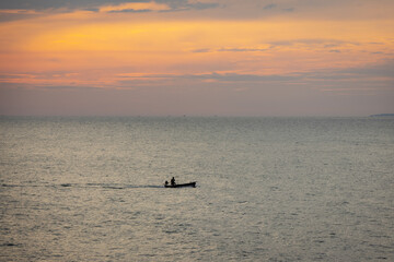 silhouette lone boat cuts through the calm waters as the sun begins its descent, casting a warm glow across the horizon