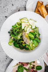 Fresh, vibrant salad featuring broccoli, cucumber, leafy greens, and a light dressing. Served in a stylish white bowl, perfect for a healthy meal or culinary presentation.