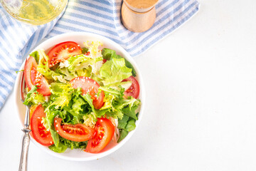 Simple minimal healthy vegetable salad with lettuce, sliced tomatoes, sesame seeds and olive oil 