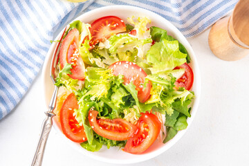 Simple minimal healthy vegetable salad with lettuce, sliced tomatoes, sesame seeds and olive oil 