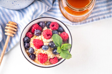 Breakfast oatmeal with fresh berries and honey/ Portioned breakfast oats with raspberry, blueberry and honey, healthy balanced morning food