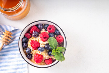 Breakfast oatmeal with fresh berries and honey/ Portioned breakfast oats with raspberry, blueberry and honey, healthy balanced morning food