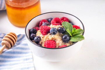 Breakfast oatmeal with fresh berries and honey/ Portioned breakfast oats with raspberry, blueberry and honey, healthy balanced morning food