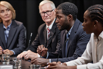 Side view of high profile African American politician speaking into microphone reporting on reform...