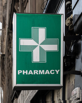  Pharmacy sign and white cross logo, symbol of reliability in chemist shop dispensing drugs and filling medical prescriptions issued by the National Health Service