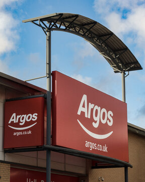 Large sign and logo over entrance to Argos store with range of goods via digital catalogue including furniture, home appliances, toys and health and beauty products
