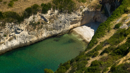 Aerial view of a bay. There is a small beach in the cove.