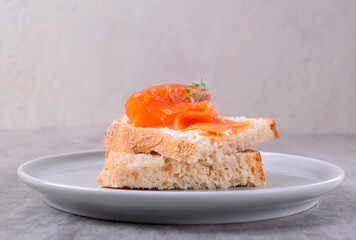 Bruschetta with smoked trout slices and cream cheese on baguette on white plate