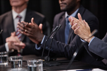 Cropped shot of female politician applauding in support of colleagues speech while sitting around...