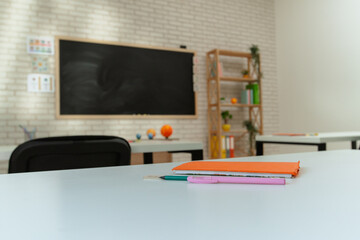 Empty school astronomy classroom with desks, chairs and chalkboard at daylight, workspace for learning and teaching. Student's seat close side shot.