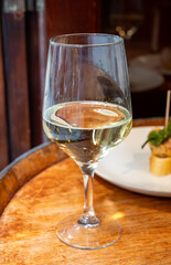 Glass of txakoli or chacolí slightly sparkling very dry white wine produced in Spanish Basque Country in typical pinchos bar in old part of San Sebastian or Donostia, Spain