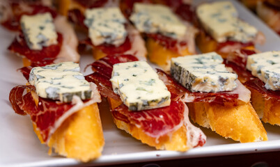 Typical snack of Basque Country, pinchos or pinxtos skewers with small pieces of bread, sea food, eggs, cheese, jamon served in bar in San-Sebastian or Bilbao, Spain, close up