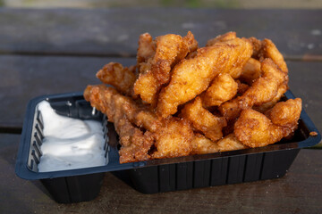 Outdoor eating of diep-fried cod fish pieces served with remoulade sauce, Dutch street food