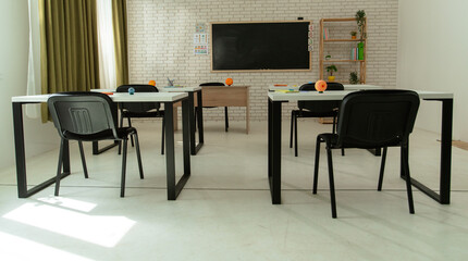 Empty school astronomy classroom with desks, chairs and chalkboard at daylight, workspace for learning teaching. Planets on student desks, full back view.