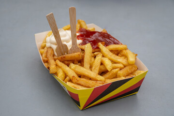 Belgian street and fast food, paper box in colors of Belgian flag with fried potato frit chips and...