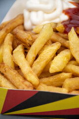 Belgian street and fast food, paper box in colors of Belgian flag with fried potato frit chips and ketchup and mayonnaise sauсe