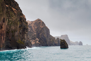 Vestmannaeyjar island is under gray dramatic sky, seaside view