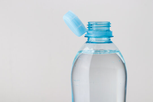 Close up of new cap attached to plastic bottle, connected to the neck of the bottle by solid tab attached to safety ring. They are intended to encourage recycling, as part of the fight against litter