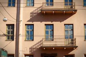 An old balconies casting shadows on brown building in old town with many wires over the road on this street