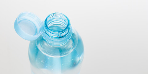 Bottle with a stationary plastic cap on a white background. The new design means the cap remains attached to the bottle after opening. Banner