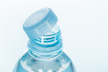 Close up of new cap attached to plastic bottle, connected to the neck of the bottle by solid tab...