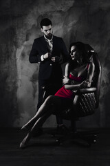 Portrait of sexual hot woman in purple dress sitting in leather chair trendy man unbutton jacket looking at bitch having erection lovely attractive couple isolated on grey dark background