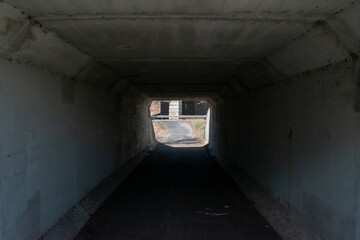 Obraz premium Early Spring Pedestrian Tunnel Under Roadway with Guardrail and Bare Trees.
