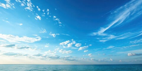 Obraz premium A serene ocean vista under a vast expanse of blue sky, adorned with wispy and fluffy clouds, a picturesque scene of tranquility