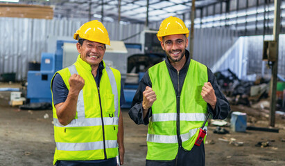 Two men in safety vests are smiling and holding their hands up in the air