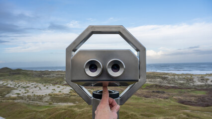 looking to the sea through binoculars positioned in the dunes