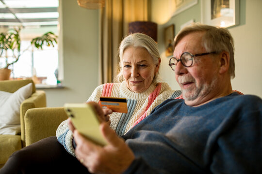 Senior couple online shopping on laptop on the couch at home