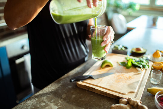 Body positive senior woman making healthy smoothie in modern kitchen